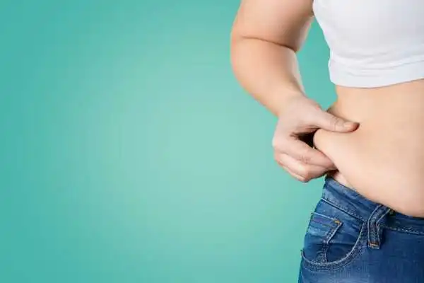 Image of woman pinching her love handles to show weight gain Bedfordshire